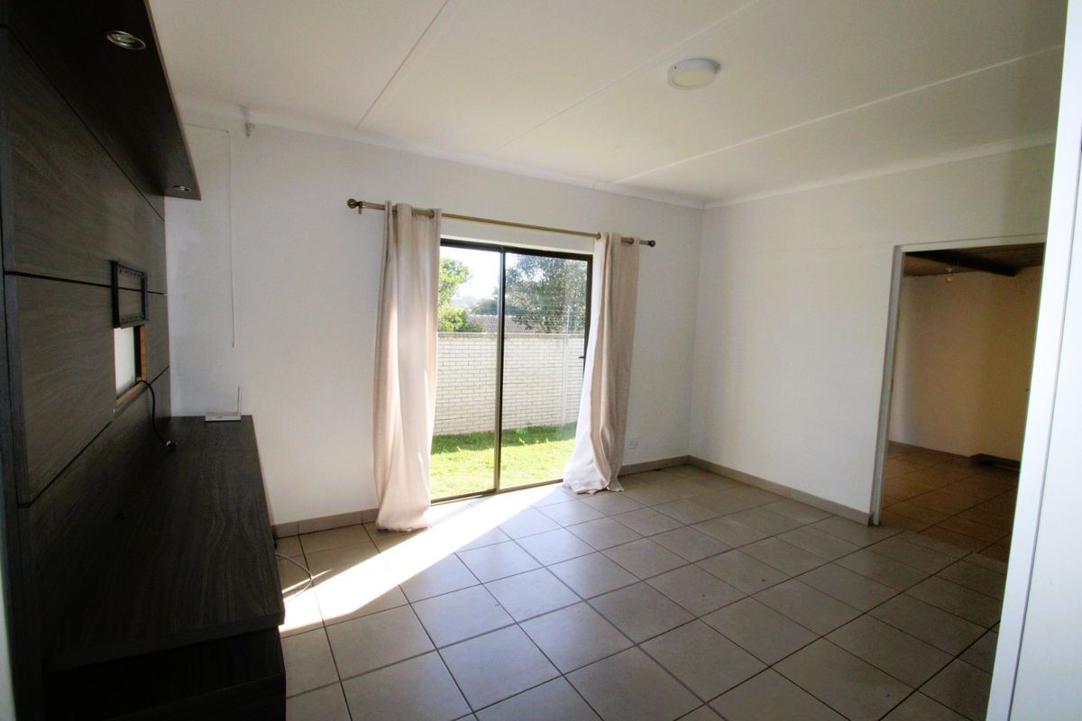 A bright, tiled living area featuring built-in cabinetry and a sliding glass door providing direct access to the rear garden.