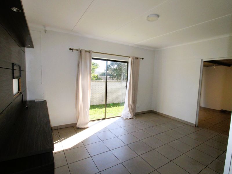 A bright, tiled living area featuring built-in cabinetry and a sliding glass door providing direct access to the rear garden.