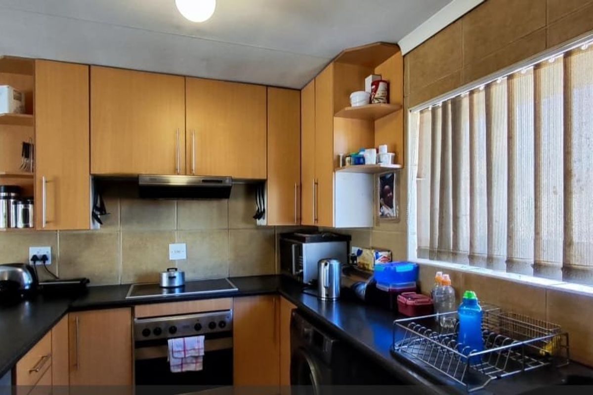 A functional kitchen featuring laminate cabinetry, built-in oven with hob, extractor fan, and tiled backsplash, offering a practical layout for daily meal preparation.