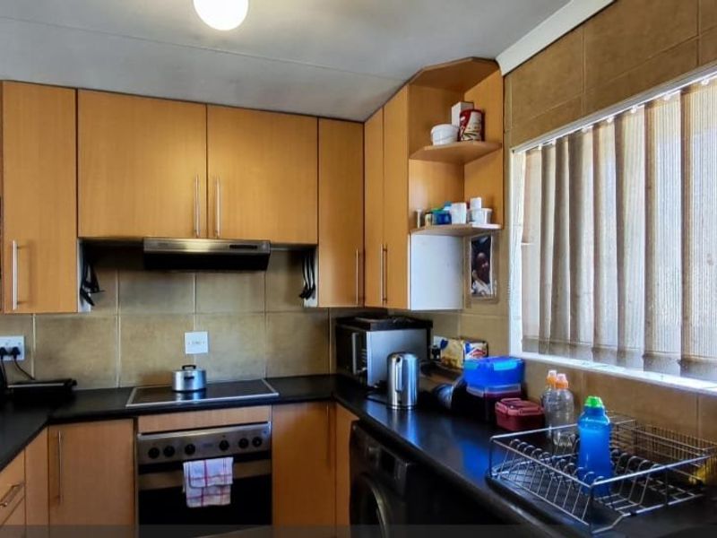 A functional kitchen featuring laminate cabinetry, built-in oven with hob, extractor fan, and tiled backsplash, offering a practical layout for daily meal preparation.