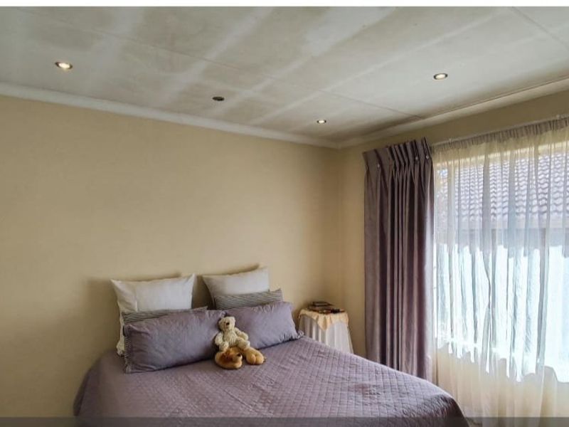 A bedroom featuring recessed downlights and curtain tracks, showing visible water staining on the ceiling.