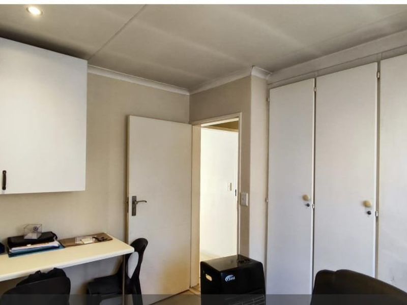 Bedroom featuring extensive built-in storage cupboards and a fitted desk area with recessed ceiling lighting.