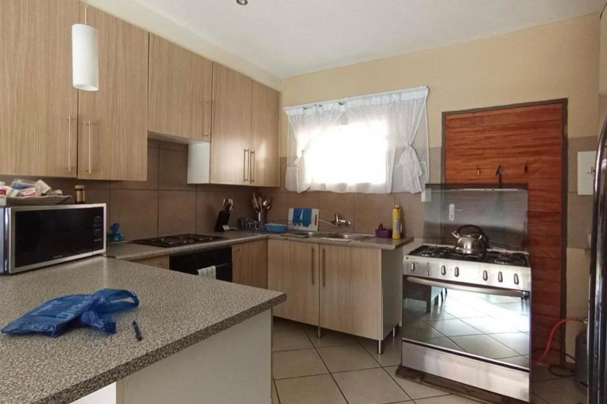 Functional kitchen featuring light wood-tone cabinetry, granite-look laminate countertops, tiled backsplash, and a gas stove, offering a practical layout for daily cooking.