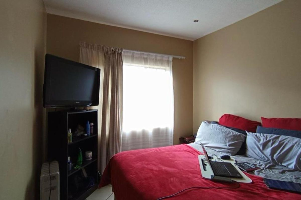 A standard bedroom featuring a window with a curtain rail and neutral wall paint.