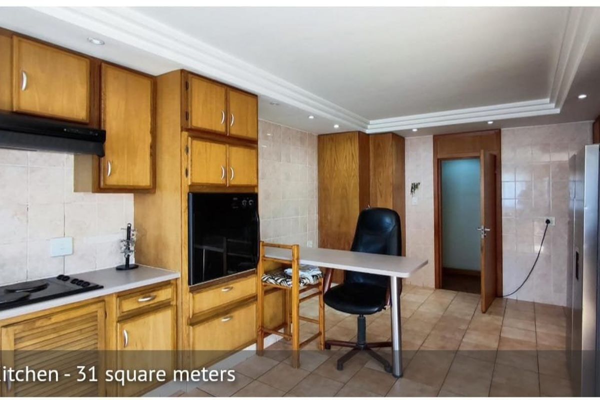 Spacious kitchen featuring wooden cabinetry, built-in oven, electric hob, and tiled finishes, offering a functional layout with ample storage space.