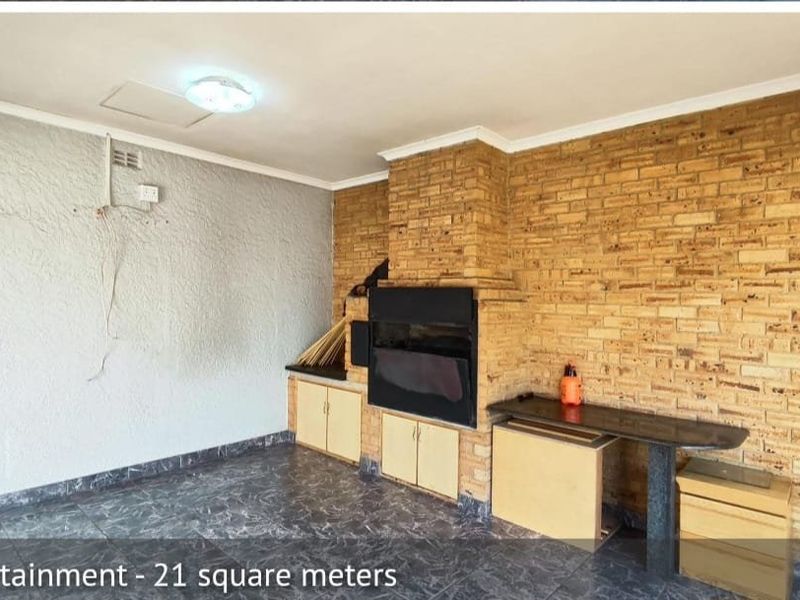 Covered entertainment area featuring a built-in braai, tiled flooring, and integrated cabinetry, offering a functional space for outdoor dining and social gatherings.