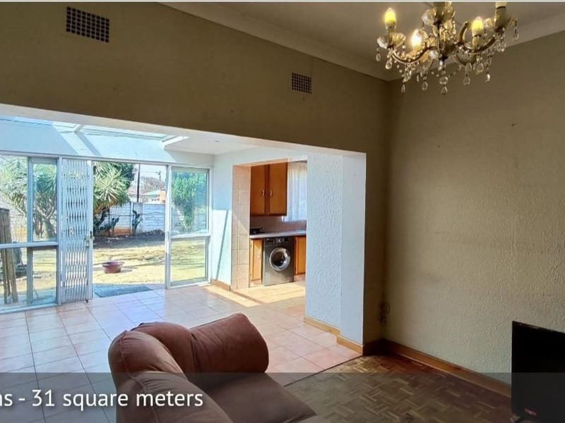 Open plan living area featuring parquet and tiled flooring, a skylight, sliding doors to the garden, and an adjoining kitchen space.