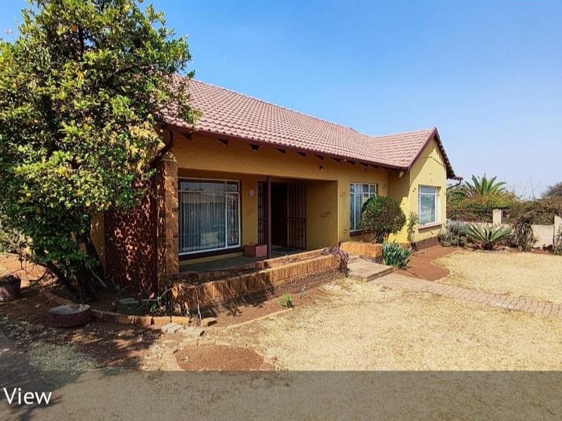 Front elevation of a single-story house featuring a tiled roof, brick accents, and a covered entrance porch set within a spacious garden.