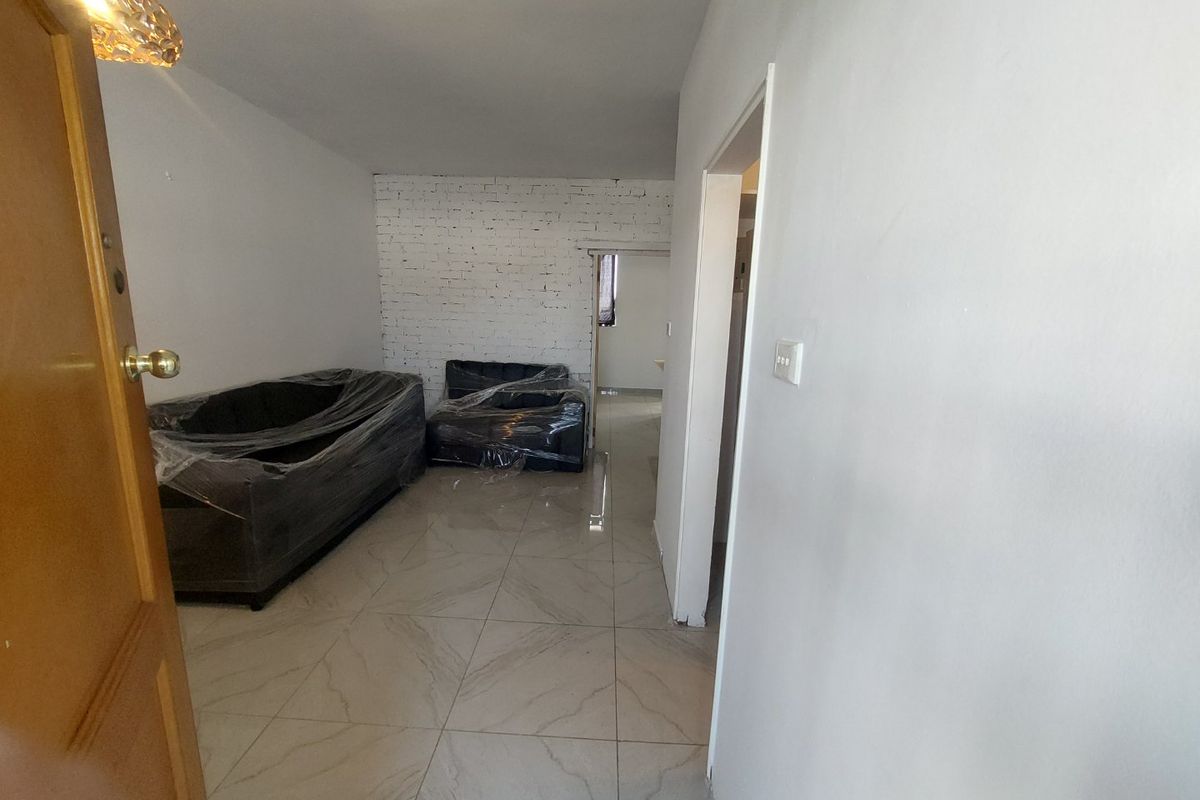 A living area featuring tiled flooring and an exposed brick feature wall, currently undergoing minor finishing work.