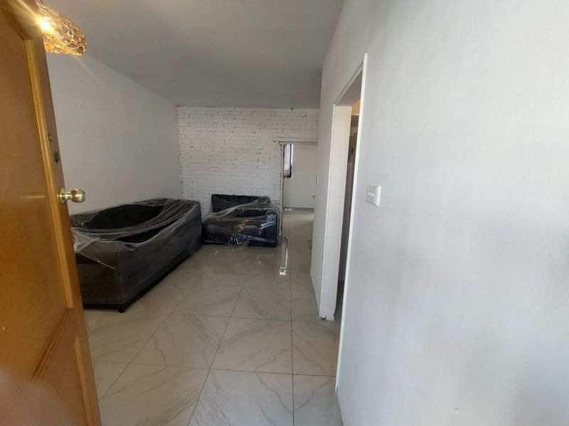 A living area featuring tiled flooring and an exposed brick feature wall, currently undergoing minor finishing work.