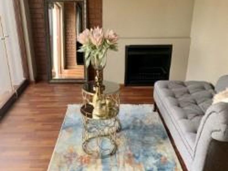 A cozy living room featuring a brick accent wall, a built-in fireplace, and warm-toned laminate flooring.