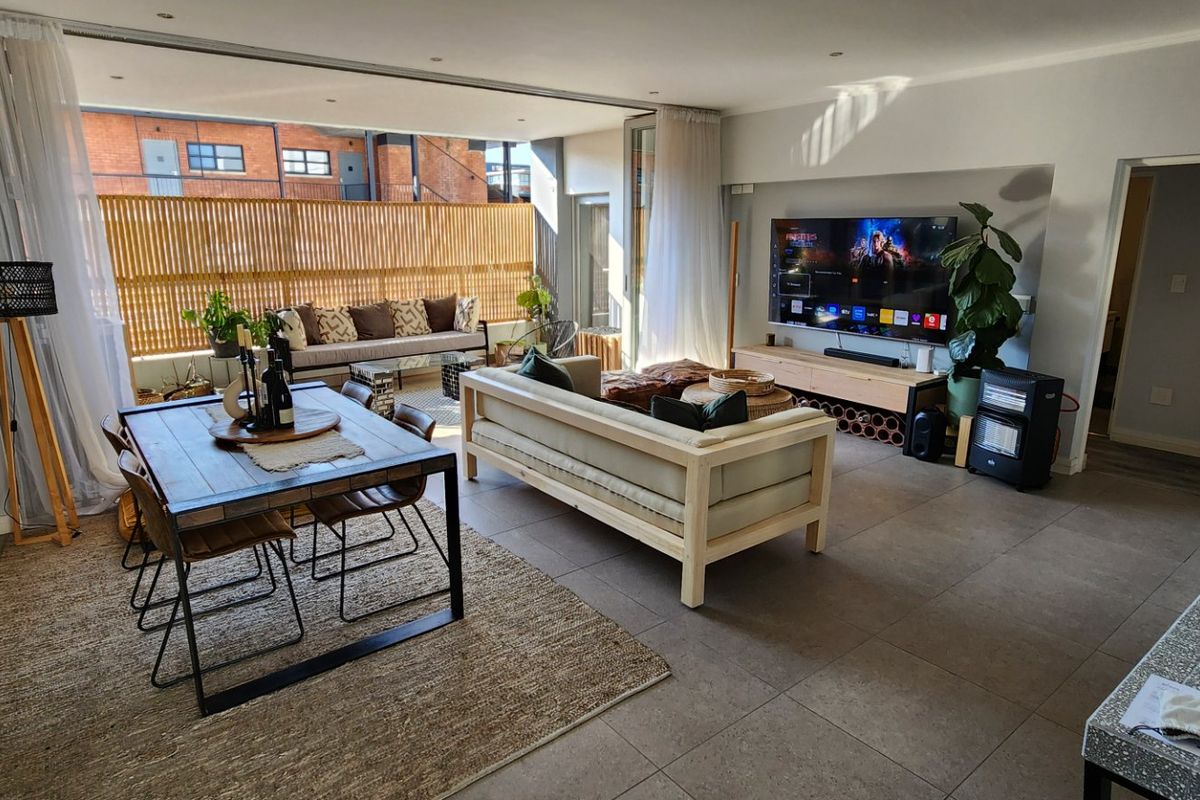 Spacious open-plan living and dining area featuring large sliding glass doors that open onto a private balcony with a timber privacy screen.