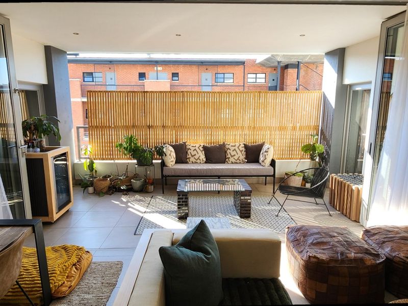 A spacious covered balcony featuring tiled flooring, recessed lighting, and a timber privacy screen, offering a seamless transition from the indoor living area.