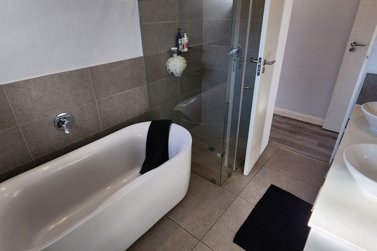 Modern bathroom featuring a freestanding bathtub, glass-enclosed shower, and a double vanity with vessel sinks and contemporary chrome fixtures.