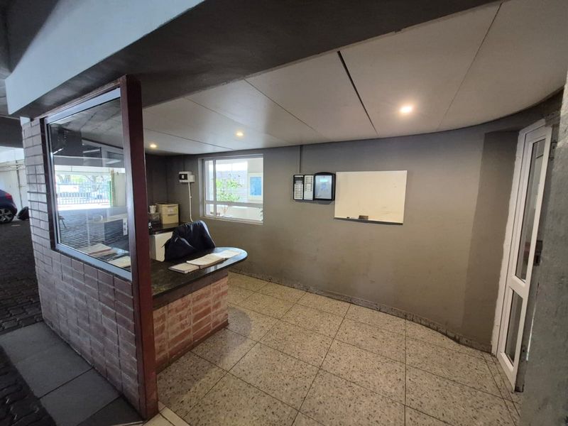 A functional building entrance or reception area featuring a brick counter, glass partition, and tiled flooring, suitable for a managed apartment complex.