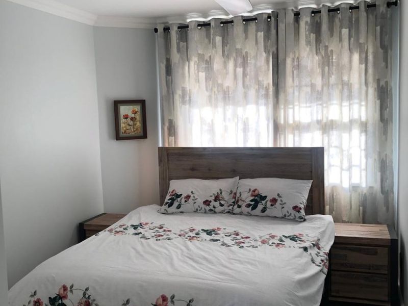 A well-maintained bedroom featuring tiled flooring, a modern ceiling fan, and recessed downlighting, creating a comfortable and functional living space.