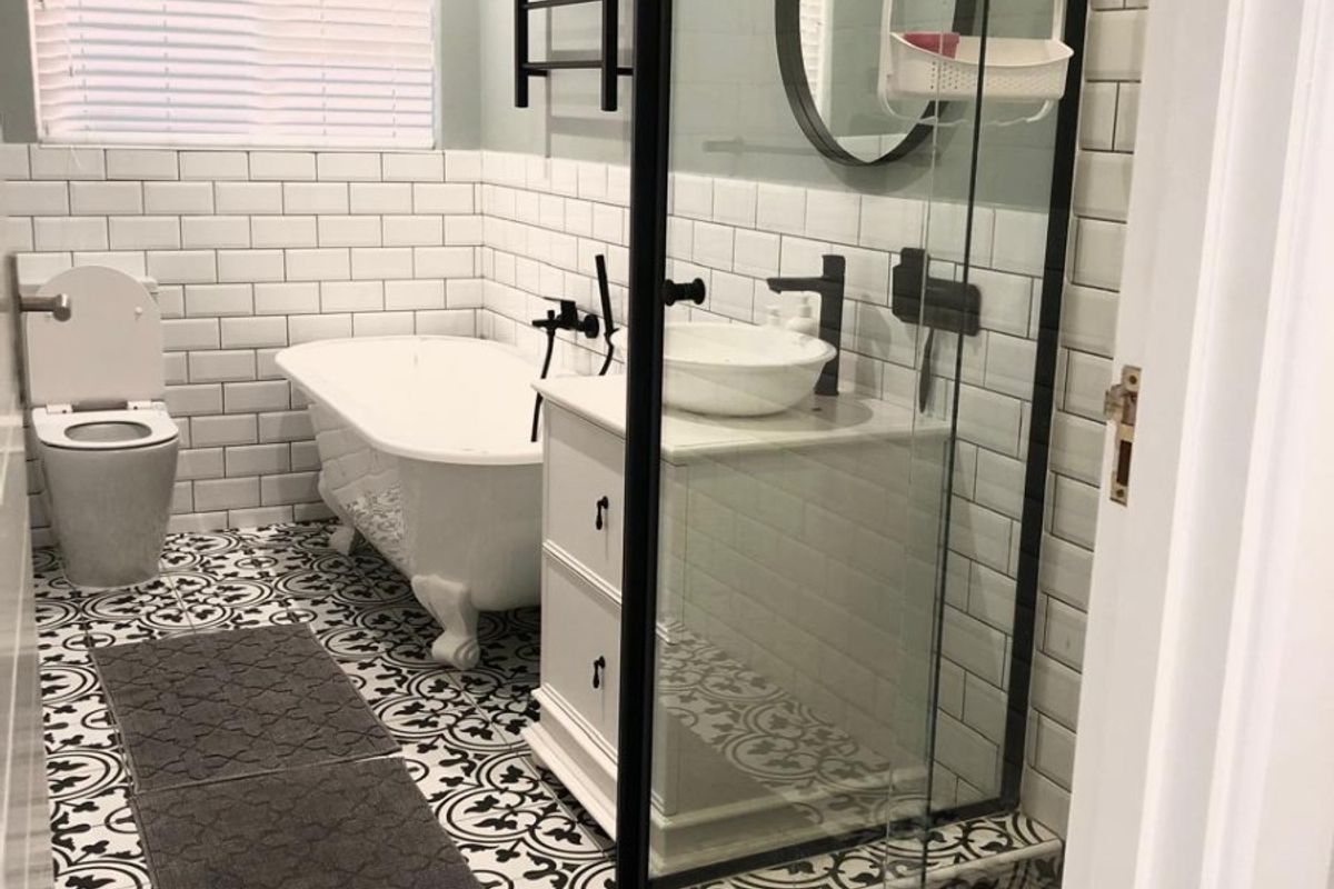 Modern bathroom featuring a freestanding bathtub, walk-in shower with black frame, vessel sink vanity, and stylish patterned floor tiles.