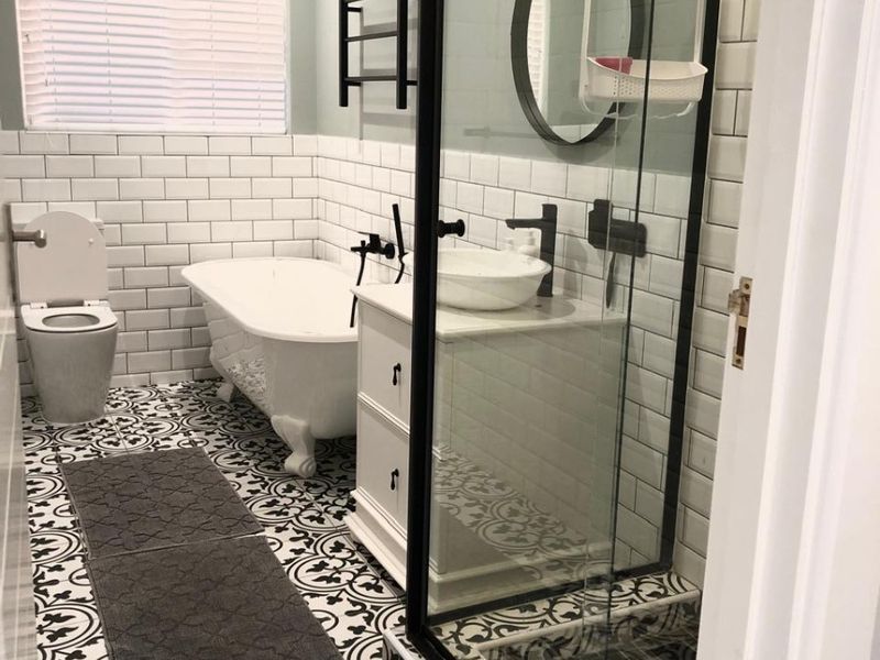 Modern bathroom featuring a freestanding bathtub, walk-in shower with black frame, vessel sink vanity, and stylish patterned floor tiles.