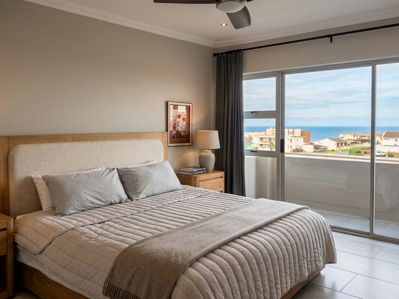 A well-maintained bedroom featuring tiled flooring, a ceiling fan, and large sliding glass doors that open to a balcony with ocean views.