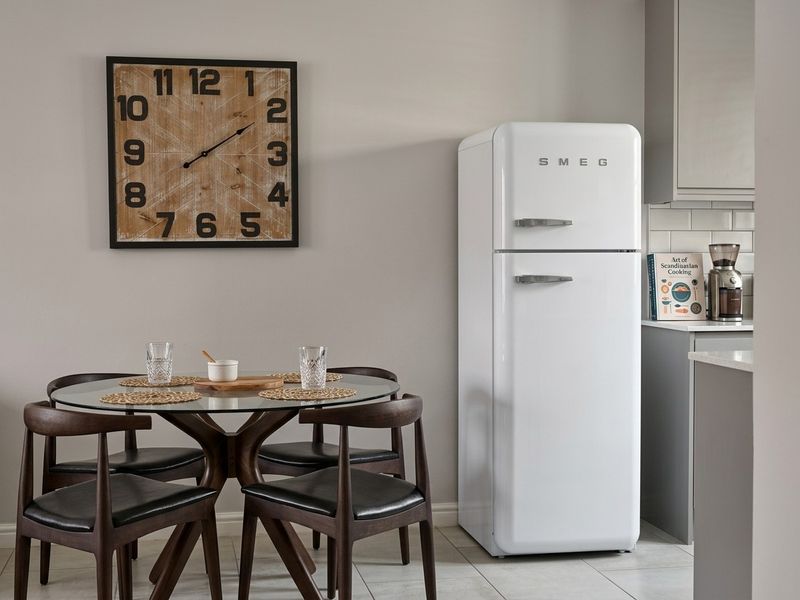A modern kitchen area featuring grey cabinetry, a subway tile backsplash, stone countertops, and tiled flooring, creating a clean and functional space.
