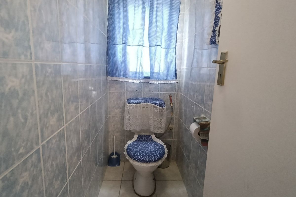 A compact bathroom featuring full-height ceramic wall tiling and a standard toilet suite.