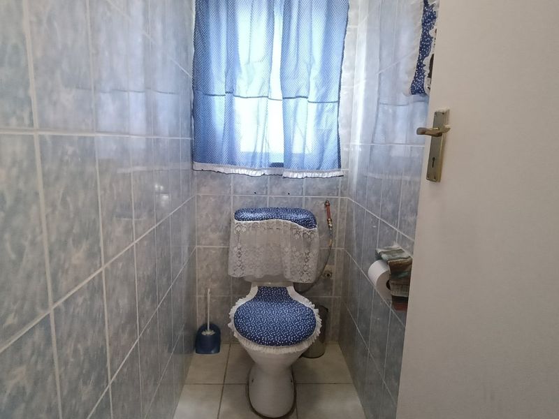 A compact bathroom featuring full-height ceramic wall tiling and a standard toilet suite.