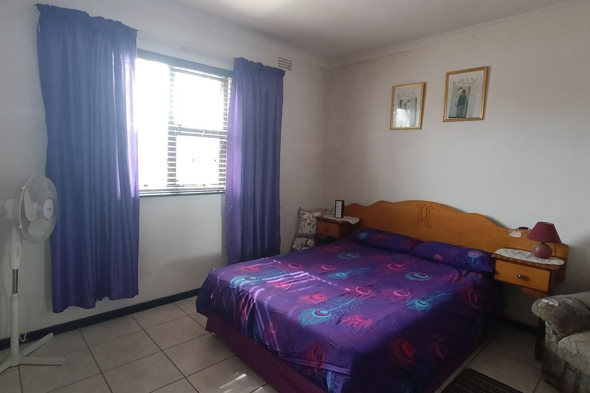 A standard bedroom featuring tiled flooring and a window with curtains, providing a functional and neutral living space.