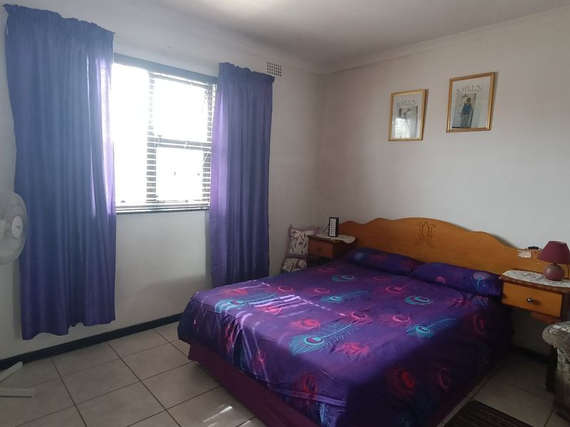 A standard bedroom featuring tiled flooring and a window with curtains, providing a functional and neutral living space.