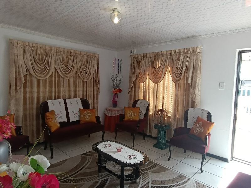 A living room featuring tiled flooring, textured ceiling, and cornicing, with direct access to the exterior.