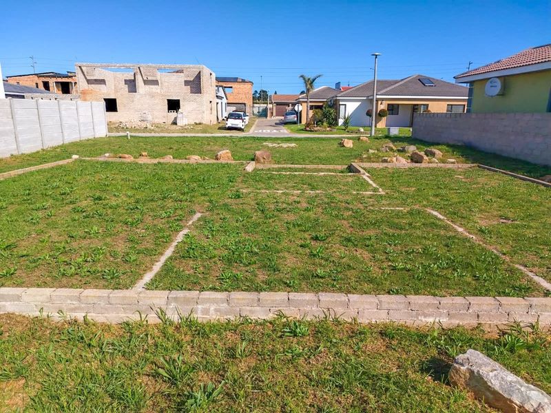 A vacant residential plot featuring a concrete foundation slab and surrounding precast boundary walls in a developing neighborhood.