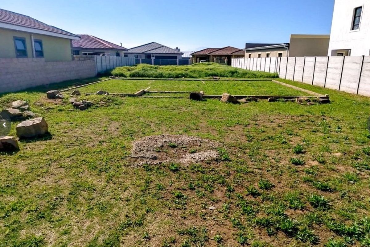 A vacant residential plot featuring precast concrete boundary walls and visible foundation footings, ready for development.