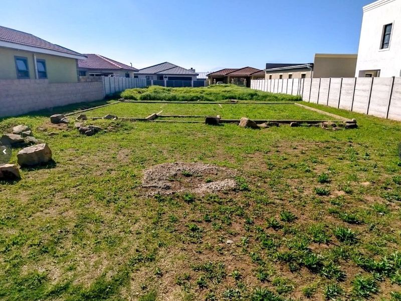 A vacant residential plot featuring precast concrete boundary walls and visible foundation footings, ready for development.