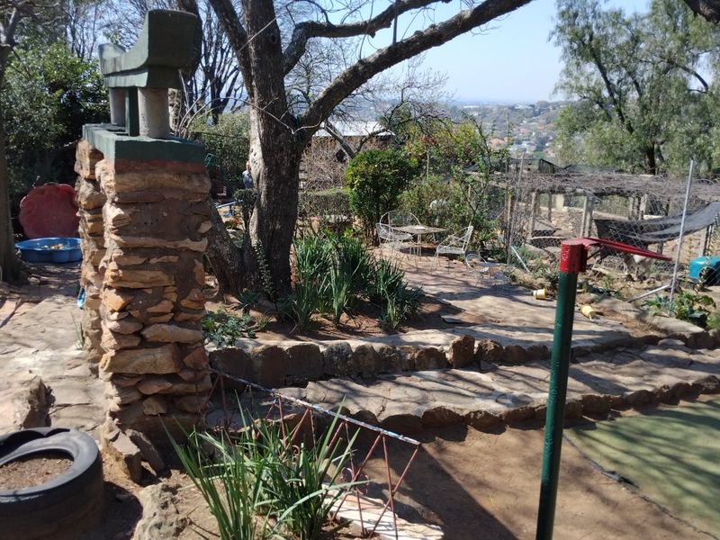 A tiered garden area featuring stone retaining walls, mature trees, and established landscaping with a view of the surrounding neighborhood.
