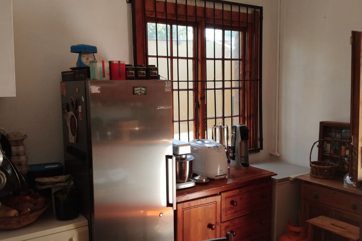 A functional kitchen area featuring timber-framed windows with security bars and built-in cabinetry, offering a practical layout for daily use.