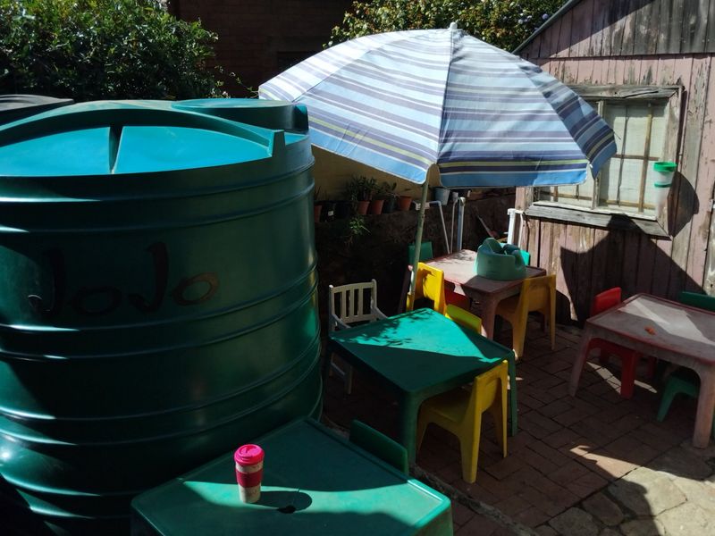 Rear outdoor area featuring a large water storage tank, paved patio space, and a weathered timber shed structure.