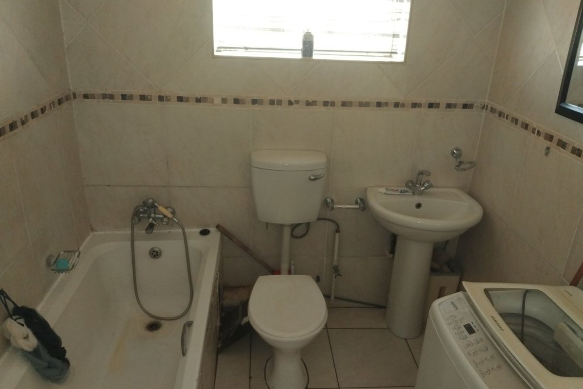A functional bathroom featuring a bathtub, pedestal basin, and toilet with tiled finishes throughout.