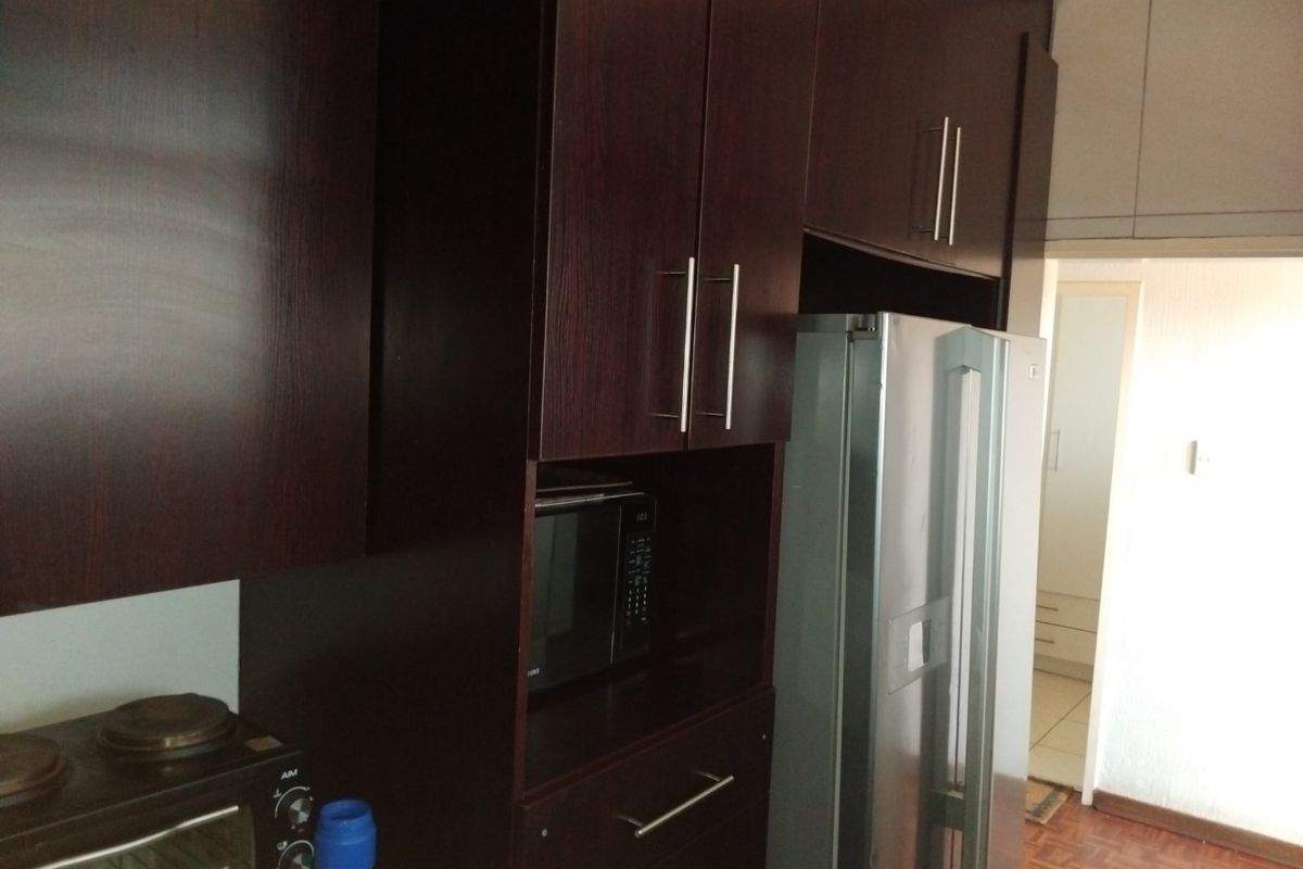 A kitchen area featuring dark wood cabinetry with integrated microwave housing and classic parquet flooring.