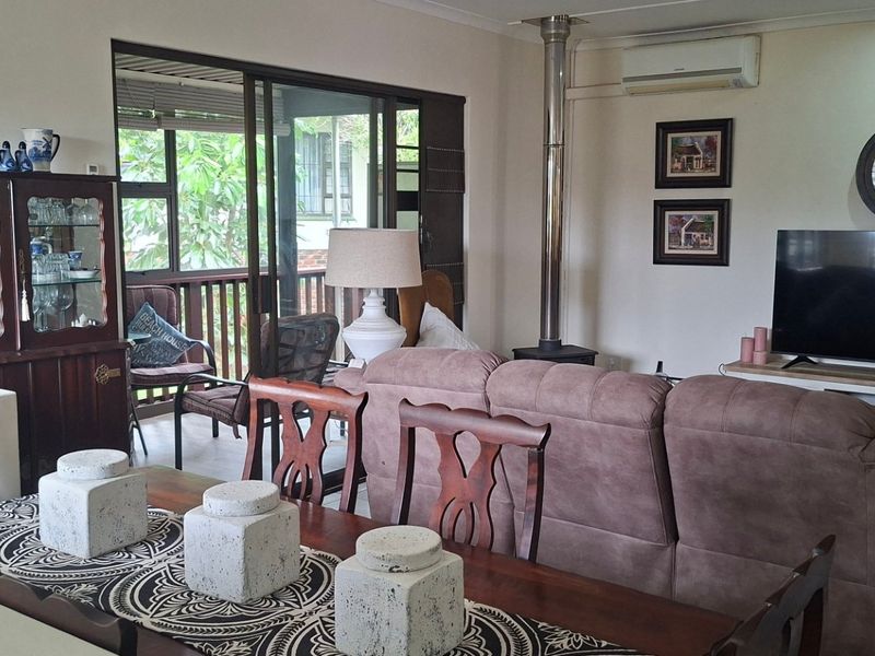 Open-plan living and dining area featuring a wood-burning fireplace, split-system air conditioning, and direct access to an outdoor balcony through sliding glass doors.