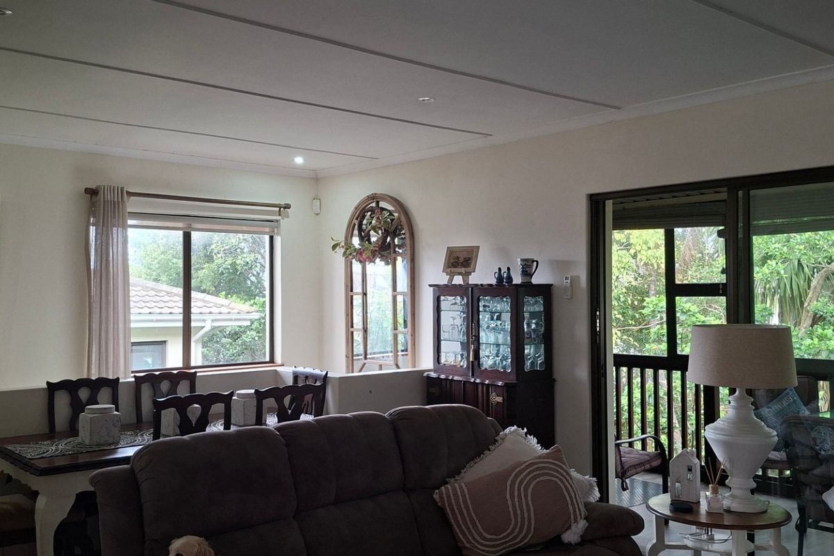 A comfortable living and dining area featuring large sliding glass doors that open onto a covered patio, providing ample natural light.