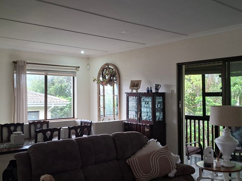 A comfortable living and dining area featuring large sliding glass doors that open onto a covered patio, providing ample natural light.