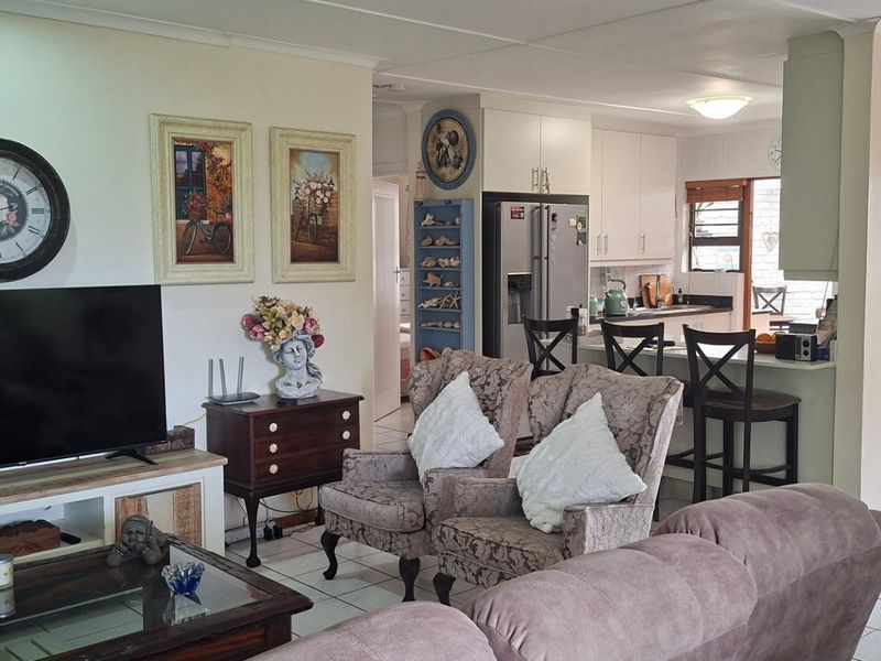 An open-plan living area featuring tiled flooring and a functional kitchen with a breakfast bar, creating a connected and versatile living space.