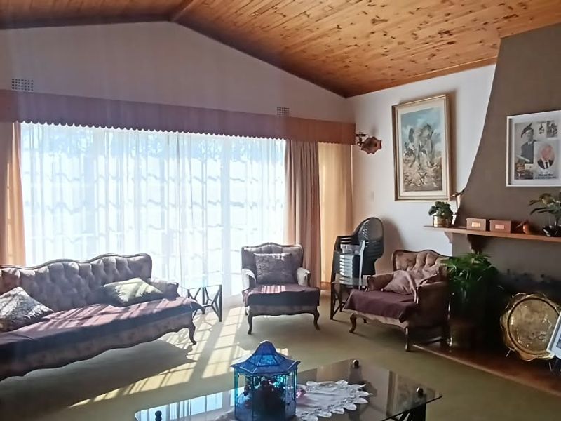 Spacious living room featuring a vaulted timber ceiling, a prominent built-in fireplace with a timber mantel, and large sliding doors providing natural light.