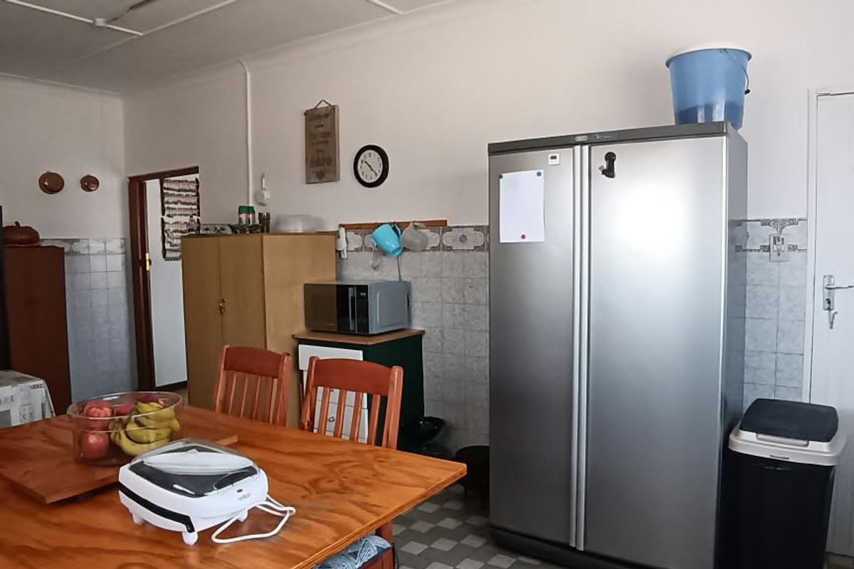 A functional kitchen area featuring tiled splashbacks, vinyl flooring, and built-in cabinetry, offering potential for modernization and aesthetic updates.