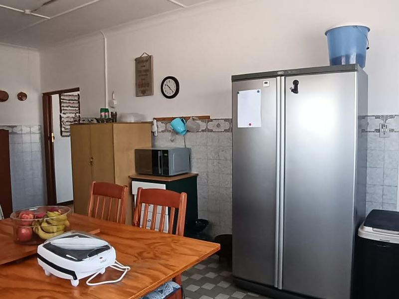 A functional kitchen area featuring tiled splashbacks, vinyl flooring, and built-in cabinetry, offering potential for modernization and aesthetic updates.