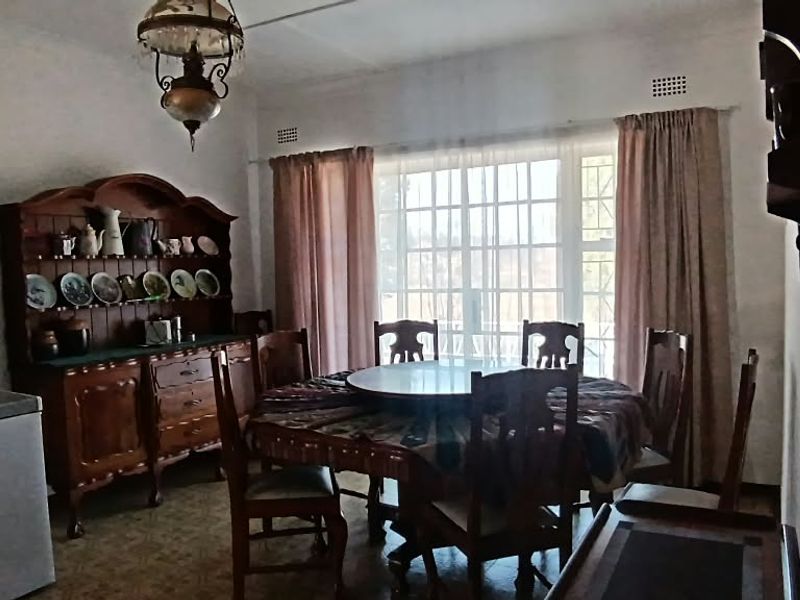 A dining room featuring a large window, ceiling light fixture, and ventilation grilles, offering a functional space for family meals.
