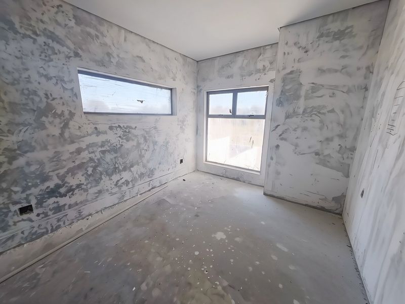 An unfinished bedroom interior featuring bare plastered walls and screeded floors, awaiting final finishes and flooring installation.
