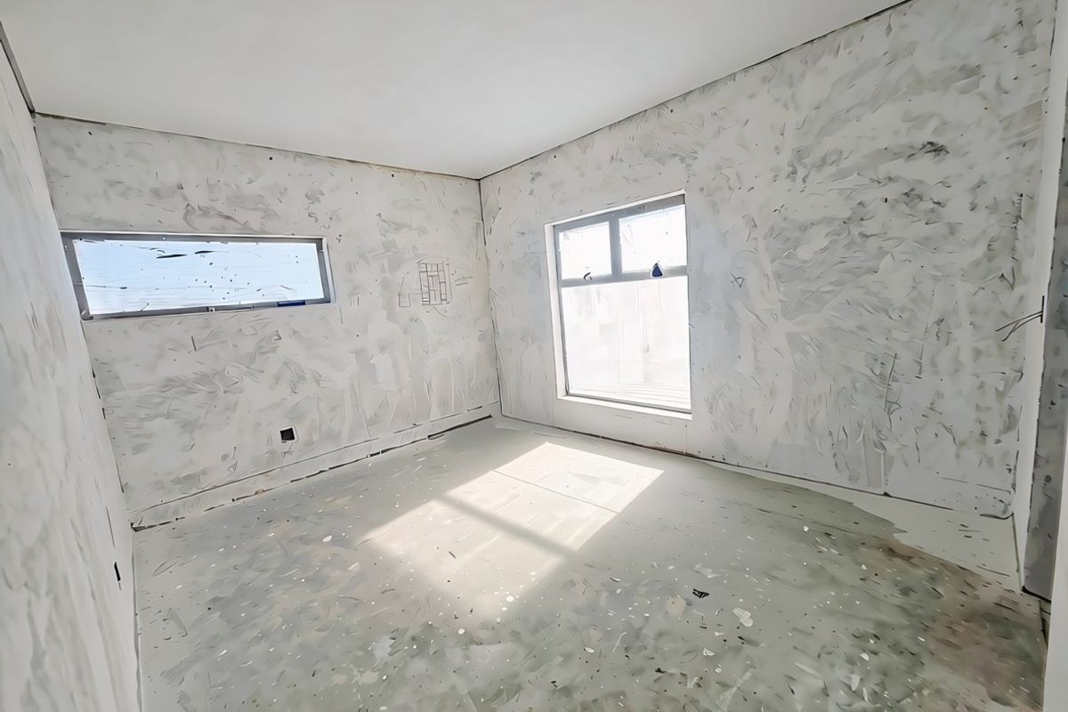 An unfinished bedroom space featuring bare plastered walls and concrete flooring, awaiting final finishes and flooring installation.