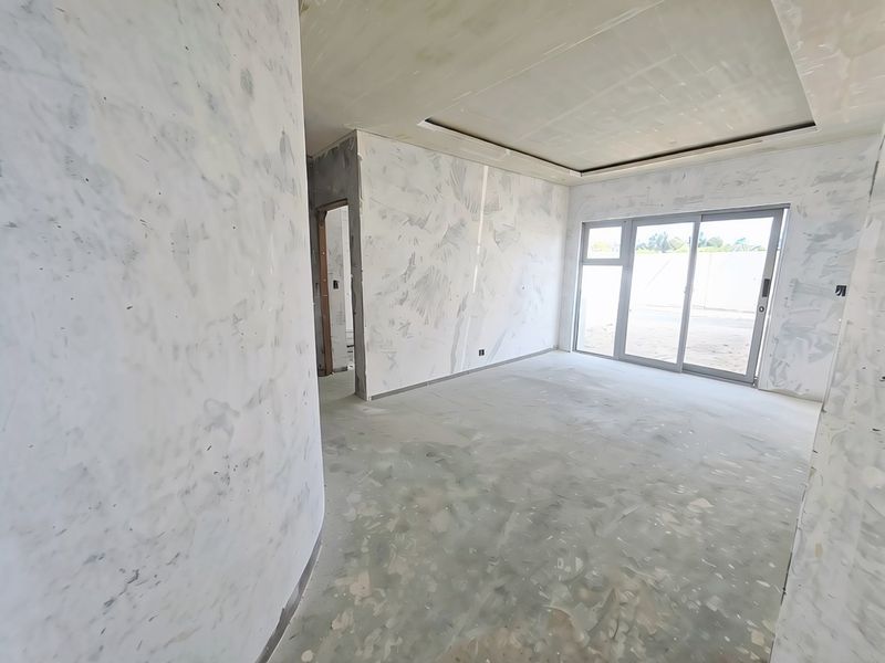 An unfinished living room space featuring a curved wall, recessed ceiling detail, and large sliding glass doors leading to the exterior.