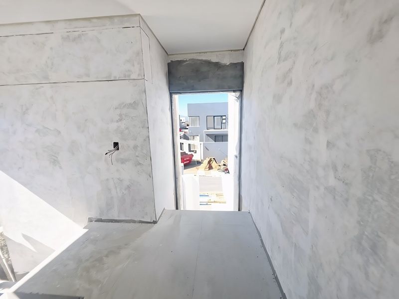 An unfinished interior hallway space showing raw plastered walls and exposed electrical wiring, currently in the construction phase.