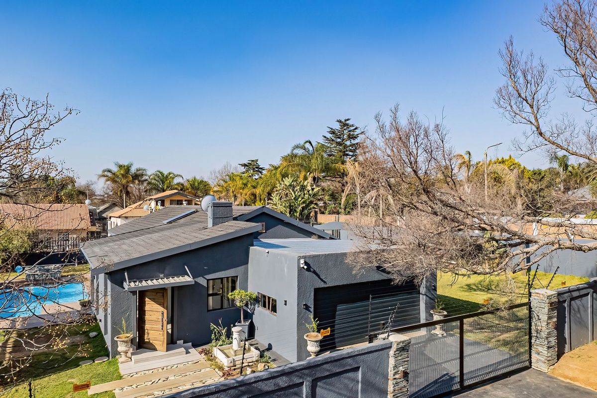 Aerial view of a modern grey-painted house featuring a swimming pool, attached garage, and landscaped garden area.